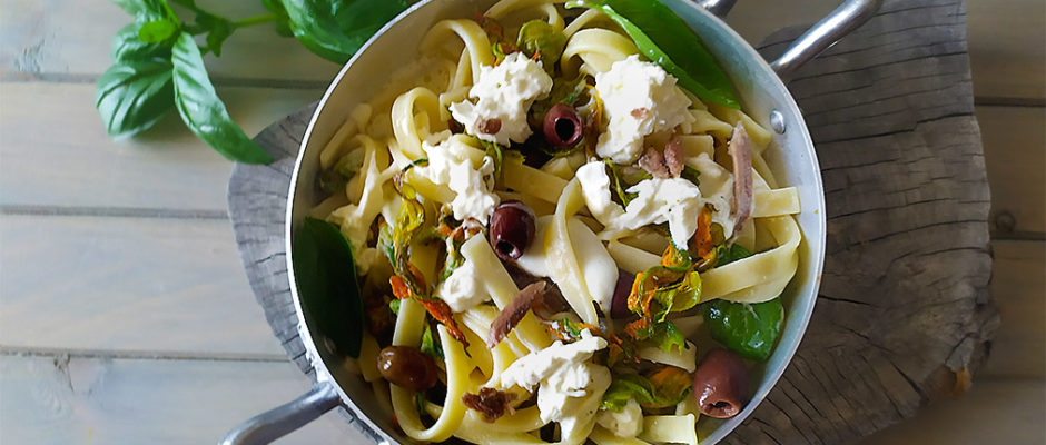 Pasta con fiori di zucca, acciughe, olive e burrata