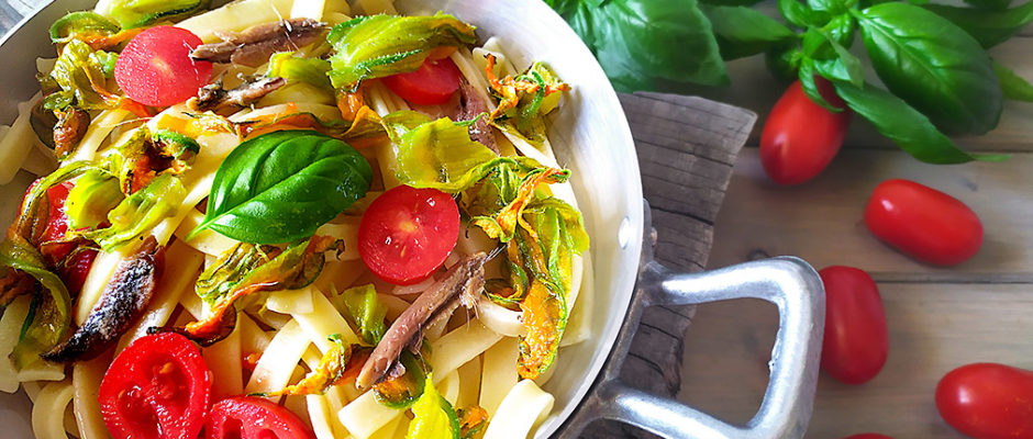 Pasta con fiori di zucca, pomodorini e acciughe